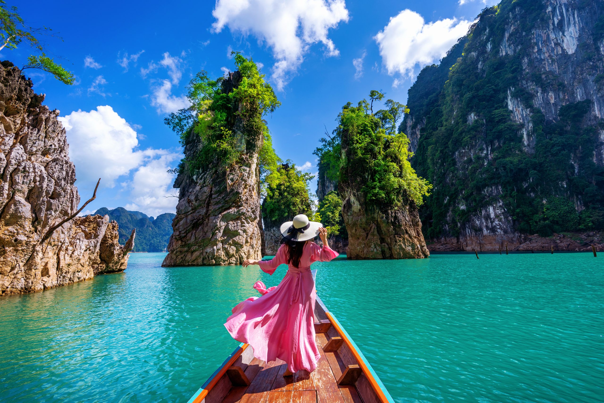 Beautiful girl standing on the boat and looking to mountains in